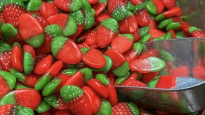 A bowl filled with an assortment of red and green candies, showcasing vibrant colors and various shapes.